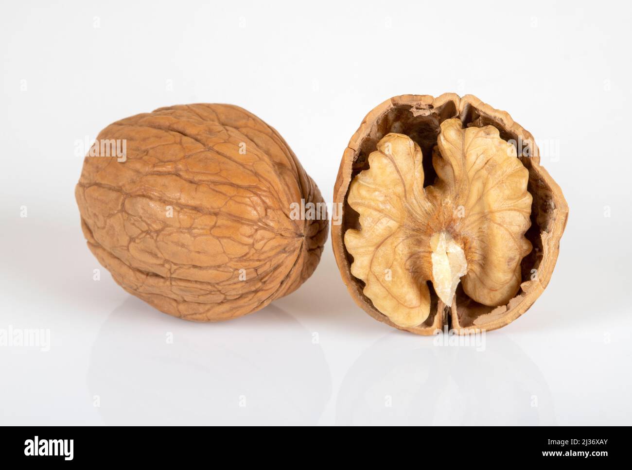 Cracked walnuts and whole walnuts on white background Stock Photo