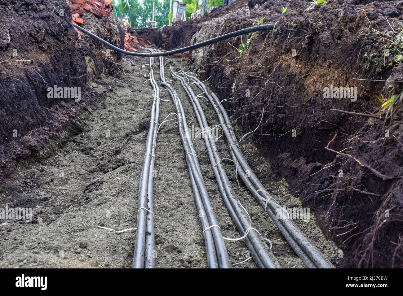 crossing of power cables laid in a trench with a base of fine gravel and protection of bricks or blocks, selective focus Stock Photo