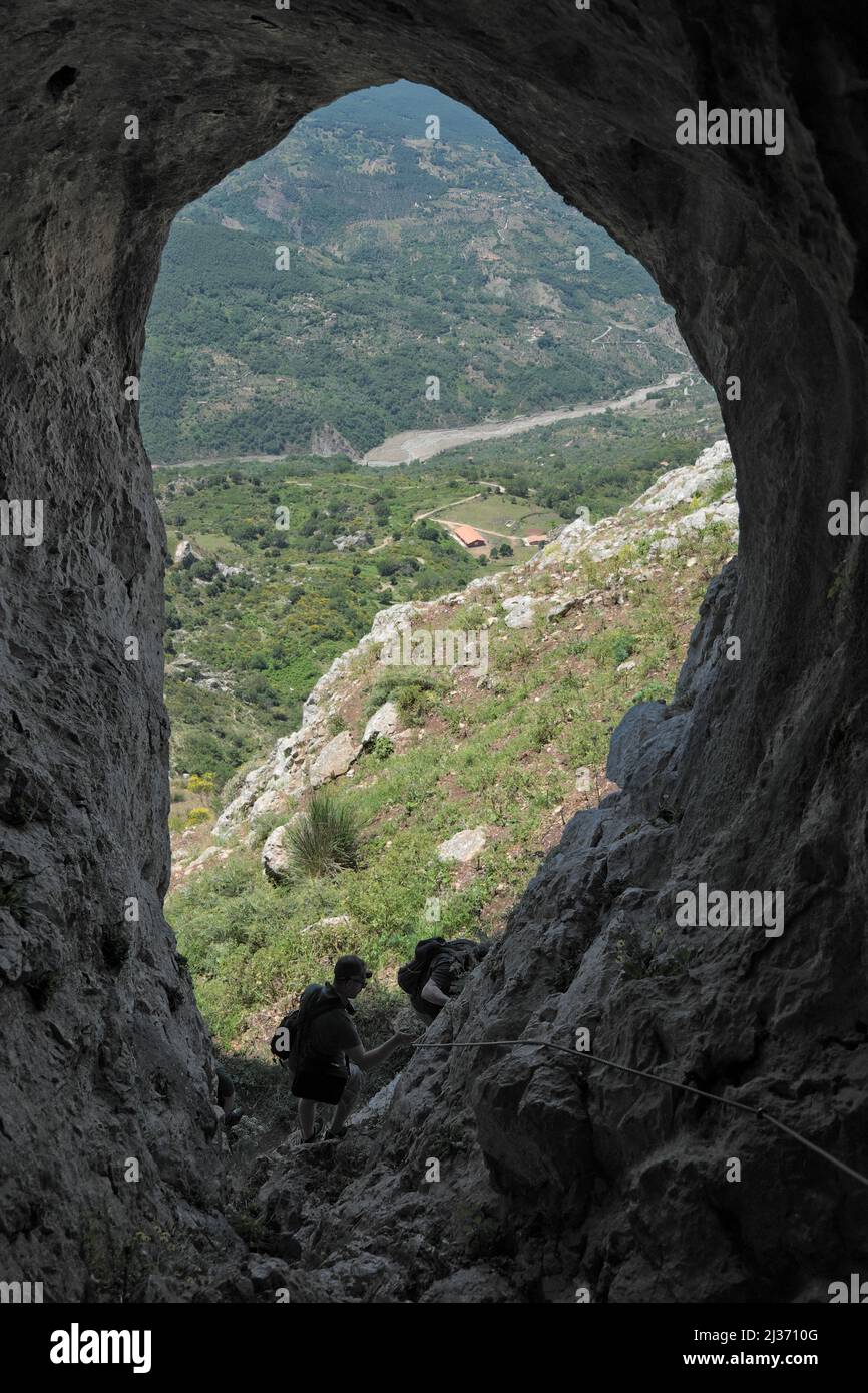 ALCARA LI FUSI, SICILY, ITALY - GIUNE 12, 2018: hikers going down on the via ferrata into tunnel of Lauro Cave that look on Rosmarino Valley in Nebrod Stock Photo