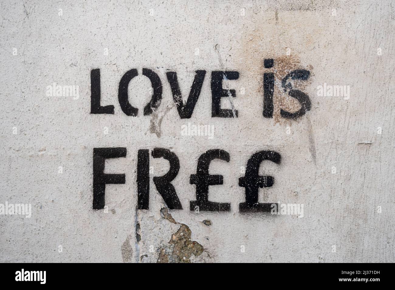 Love is Free graffiti on wall (love is fr££ with pound signs), stencil graffiti Stock Photo