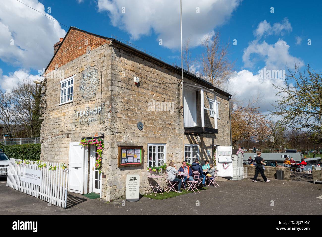 People sitting at tables outside Teashop by the Canal, by the Kennet and Avon Canal in Newbury town centre, Berkshire, England, UK Stock Photo