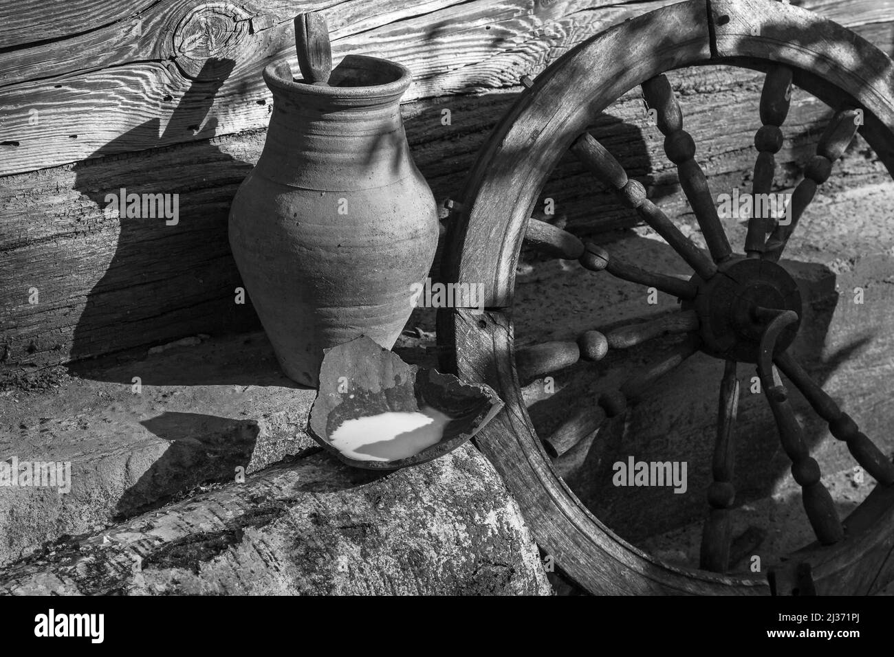 Rustic still life of old items, jug and old wheel on a wooden wall background Stock Photo