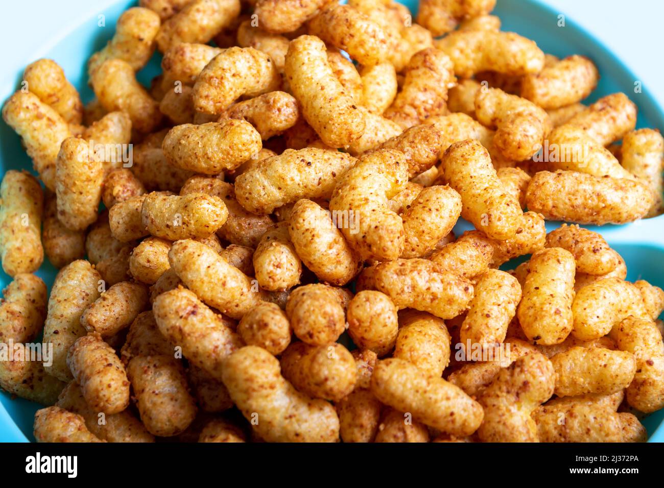 Puffed corn peanuts snacks on plate. Close-up. Stock Photo