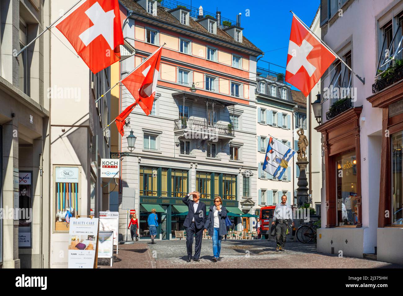 Historic city center of Zurich with Swiss flags hanging from buildings with bokeh background blur effect on a sunny day in summer, Switzerland Stock Photo