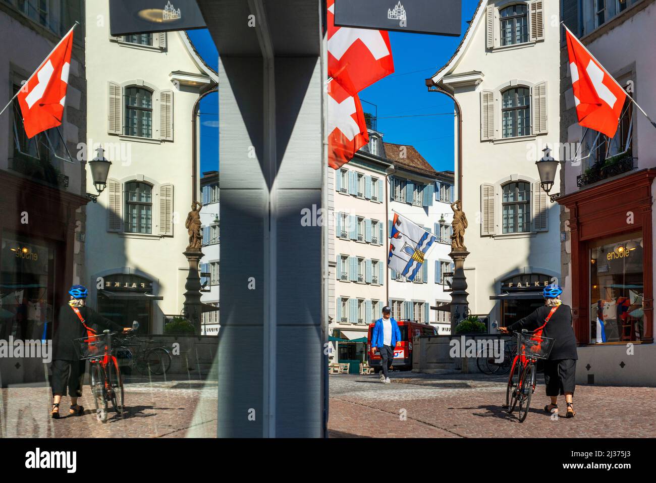 Historic city center of Zurich with Swiss flags hanging from buildings with bokeh background blur effect on a sunny day in summer, Switzerland Stock Photo