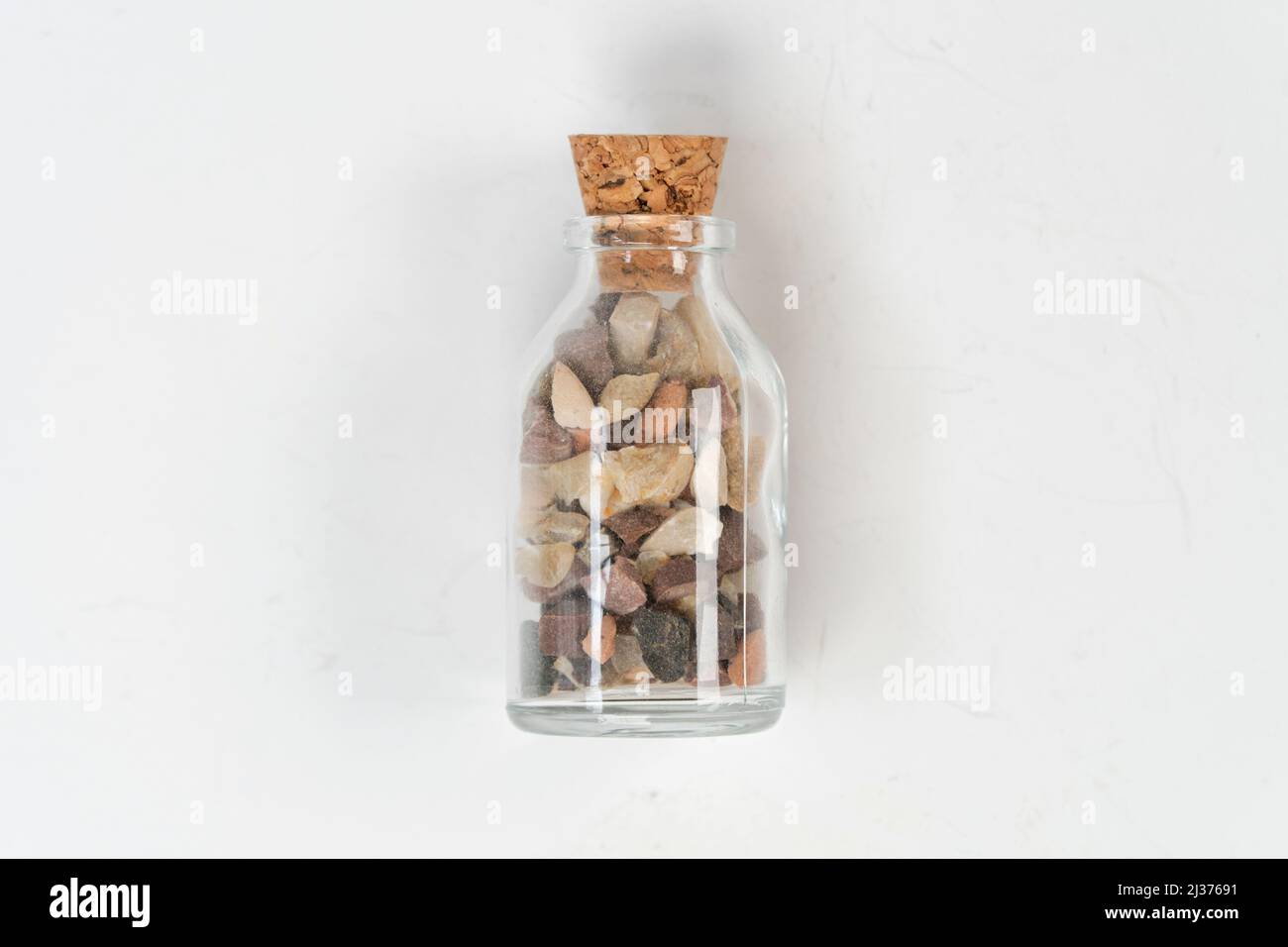 Small rocks in glass bottle with cork stopper isolated on white background, for remembrance, broken sand stones in glass bottle, saving memory on jar, Stock Photo