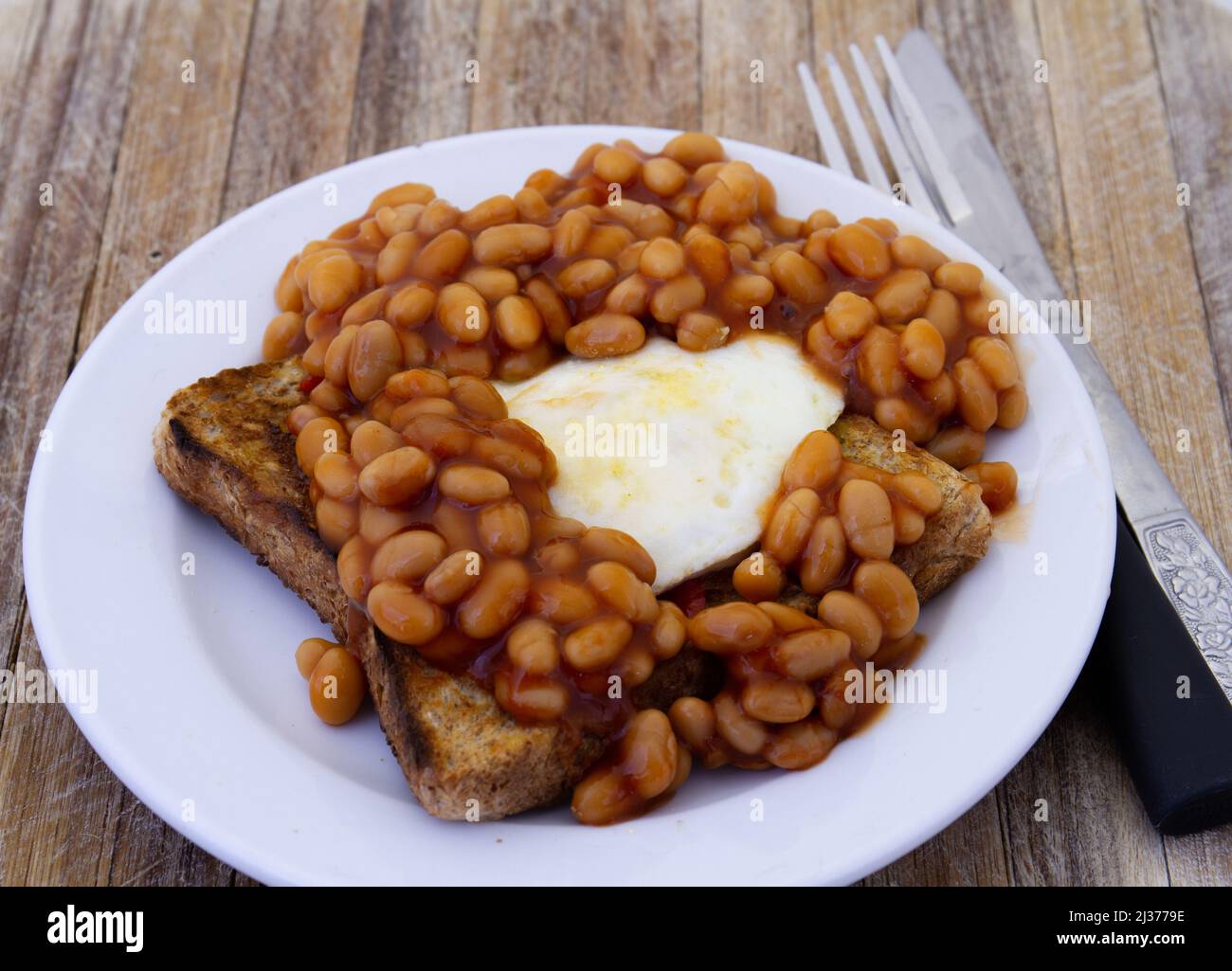 A fried egg and baked beans in tomato sauce on toast Stock Photo