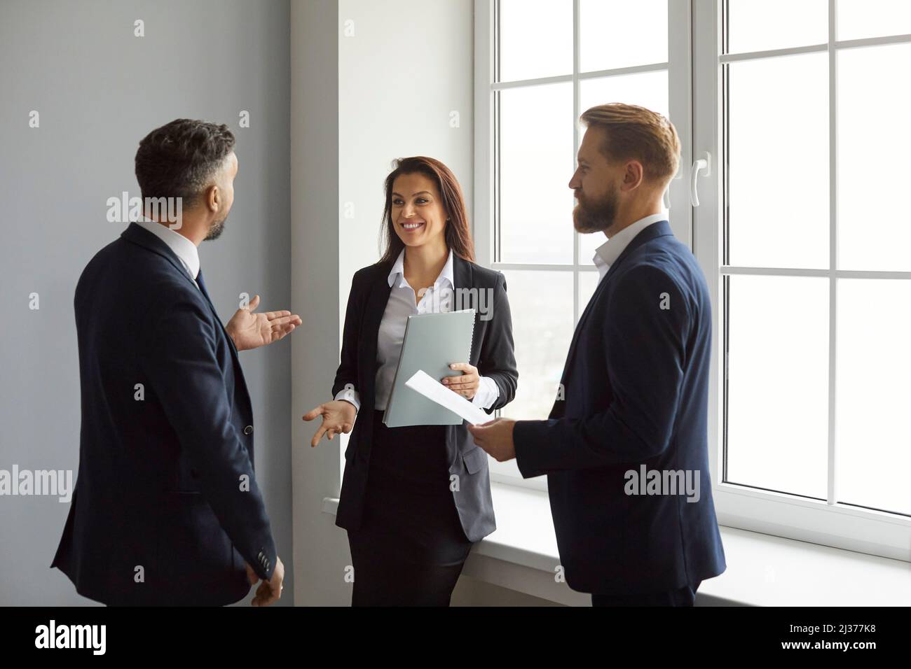Smiling business people discuss work, project strategy and exchange ideas together. Stock Photo