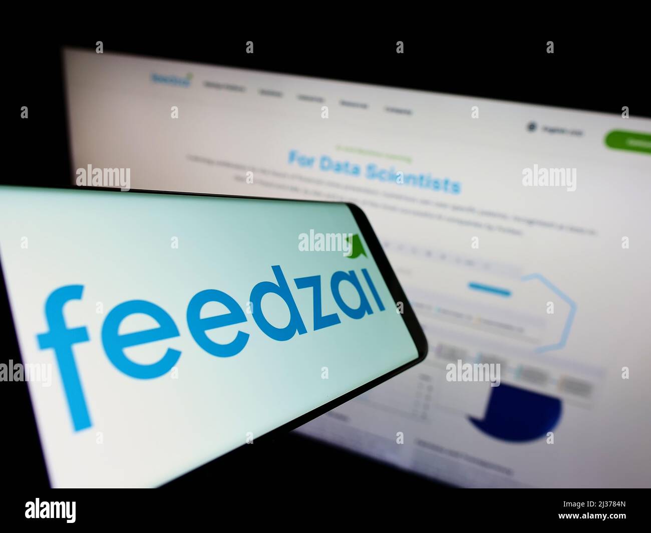 Cellphone with logo of Portuguese risk management company Feedzai on screen in front of business website. Focus on center-right of phone display. Stock Photo