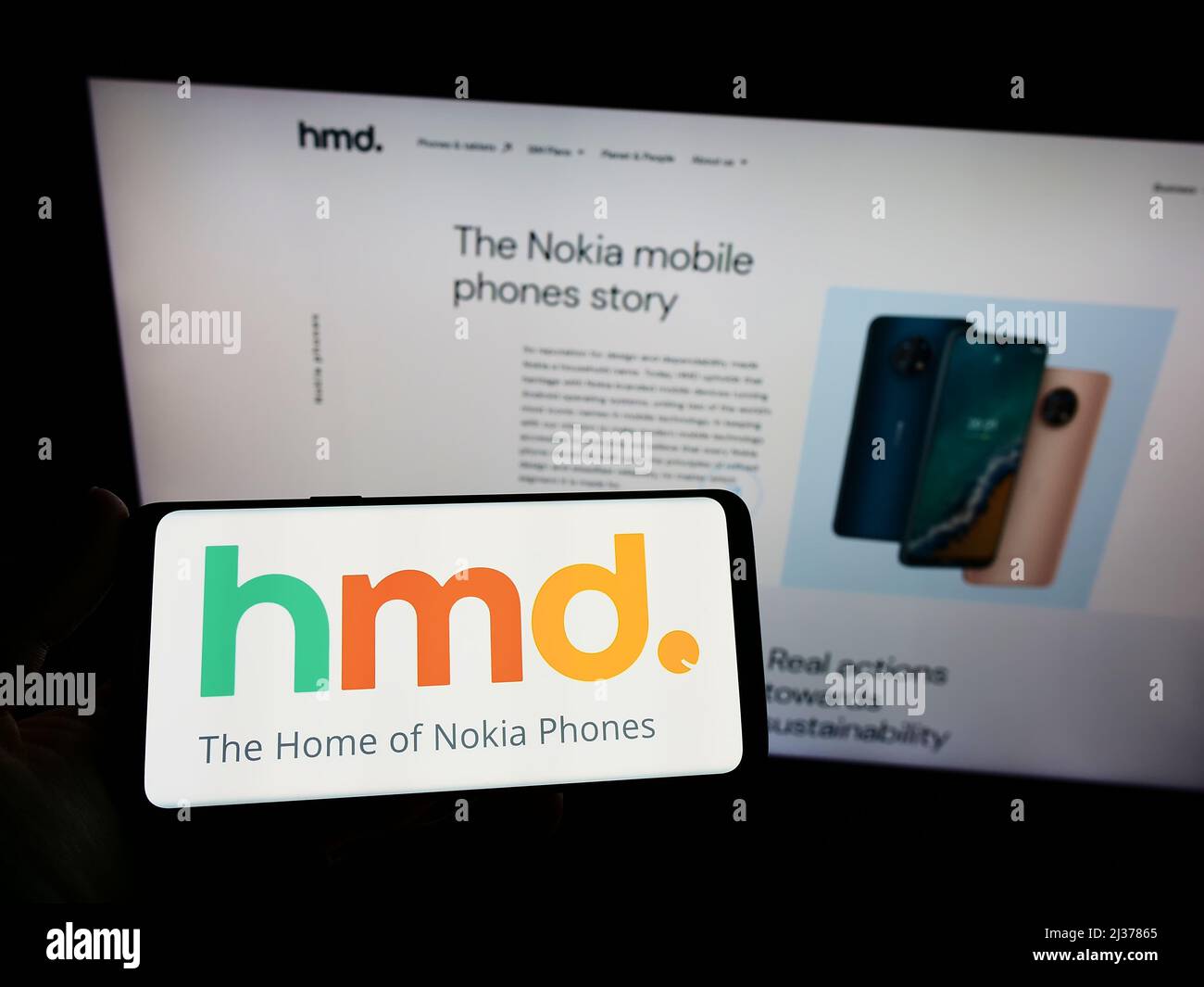 Person holding smartphone with logo of Finnish electronics company HMD Global Oy on screen in front of website. Focus on phone display. Stock Photo