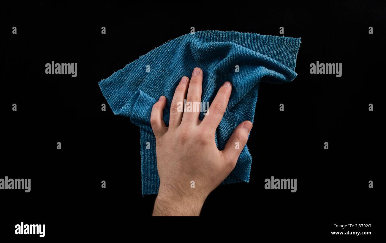 Cleaning table with blue cleaning cloth, male hand clean desk, isolated on black background, top view Stock Photo
