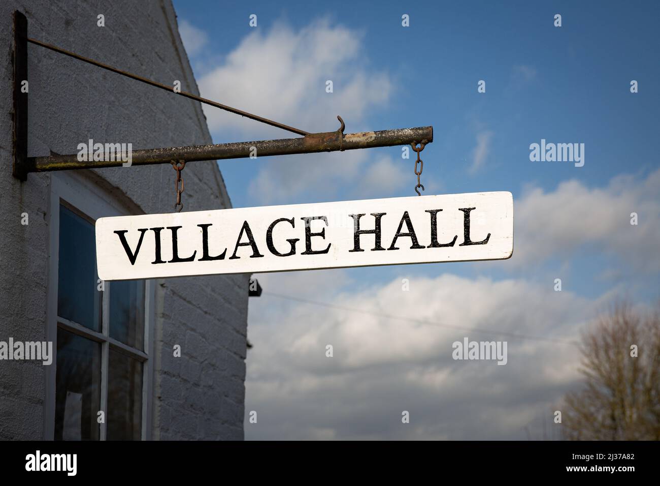 A Village Hall sign hanging from a local community building which is a meeting place for the residents of a small English neighbourhood Stock Photo