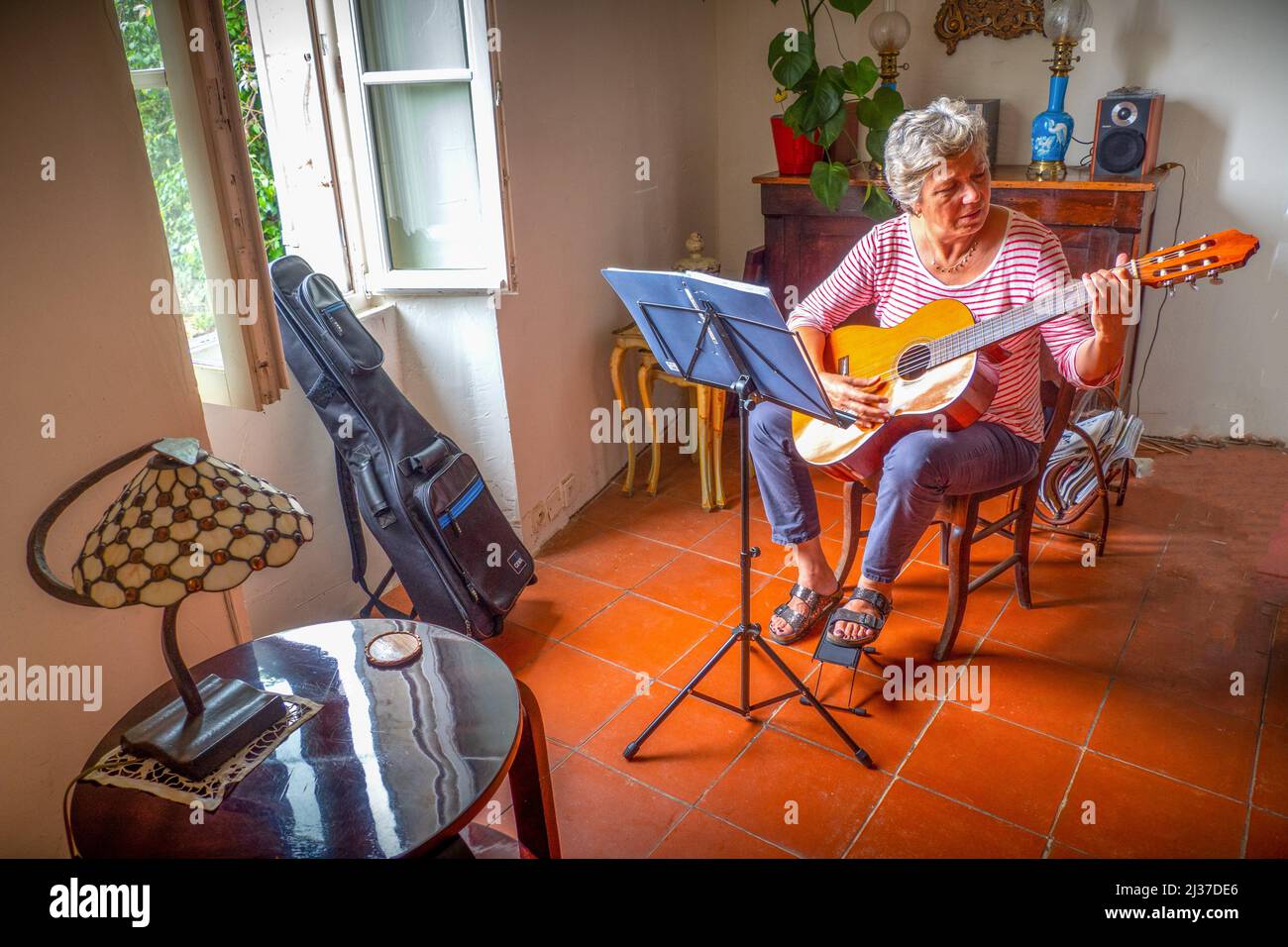 France, Occitanie, Gers Sylviee Clavaud Megevand, in there retirement home at Rozes., playing guitar. Stock Photo