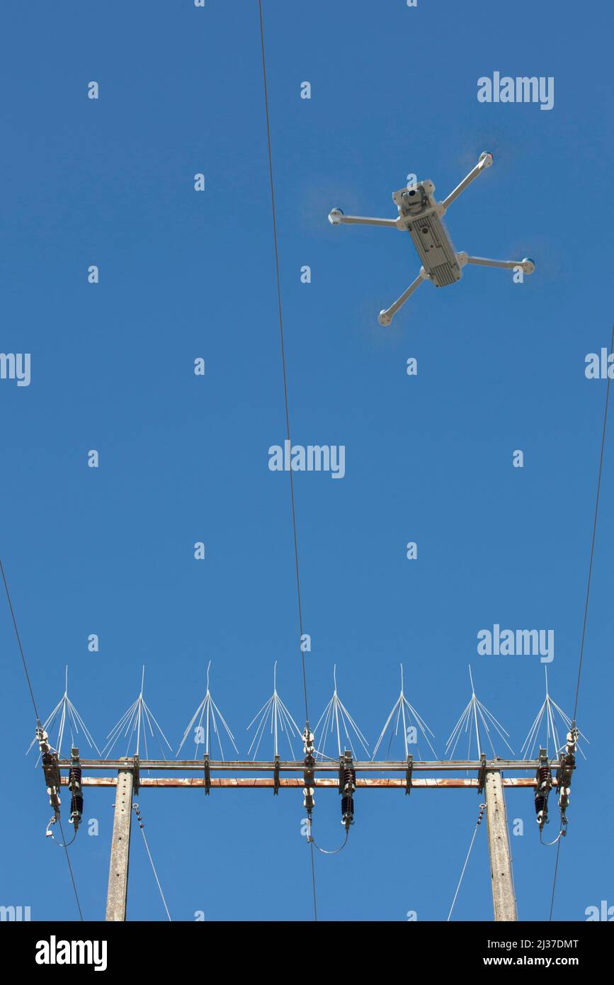 Dron flying over concrete electricity pylon. Drones for power line inspection concept. Stock Photo