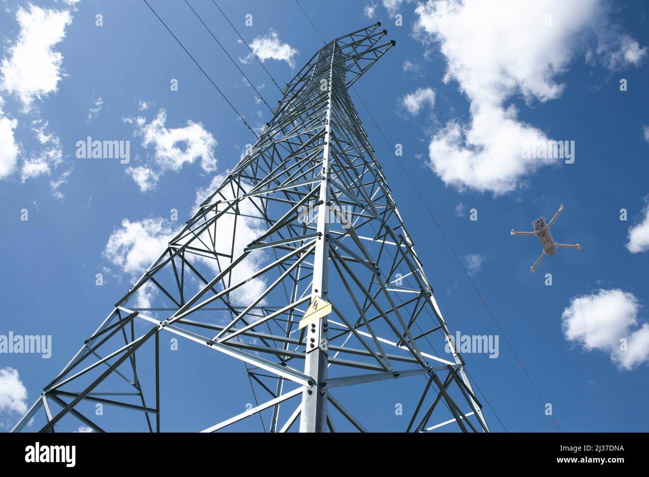 Dron flying over stell electricity pylon. Drones for power line inspection concept. Stock Photo