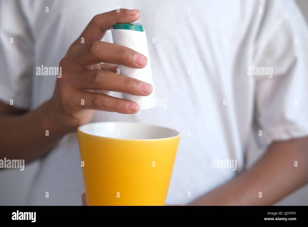 young man putting artificial sweetener in tea, Stock Photo