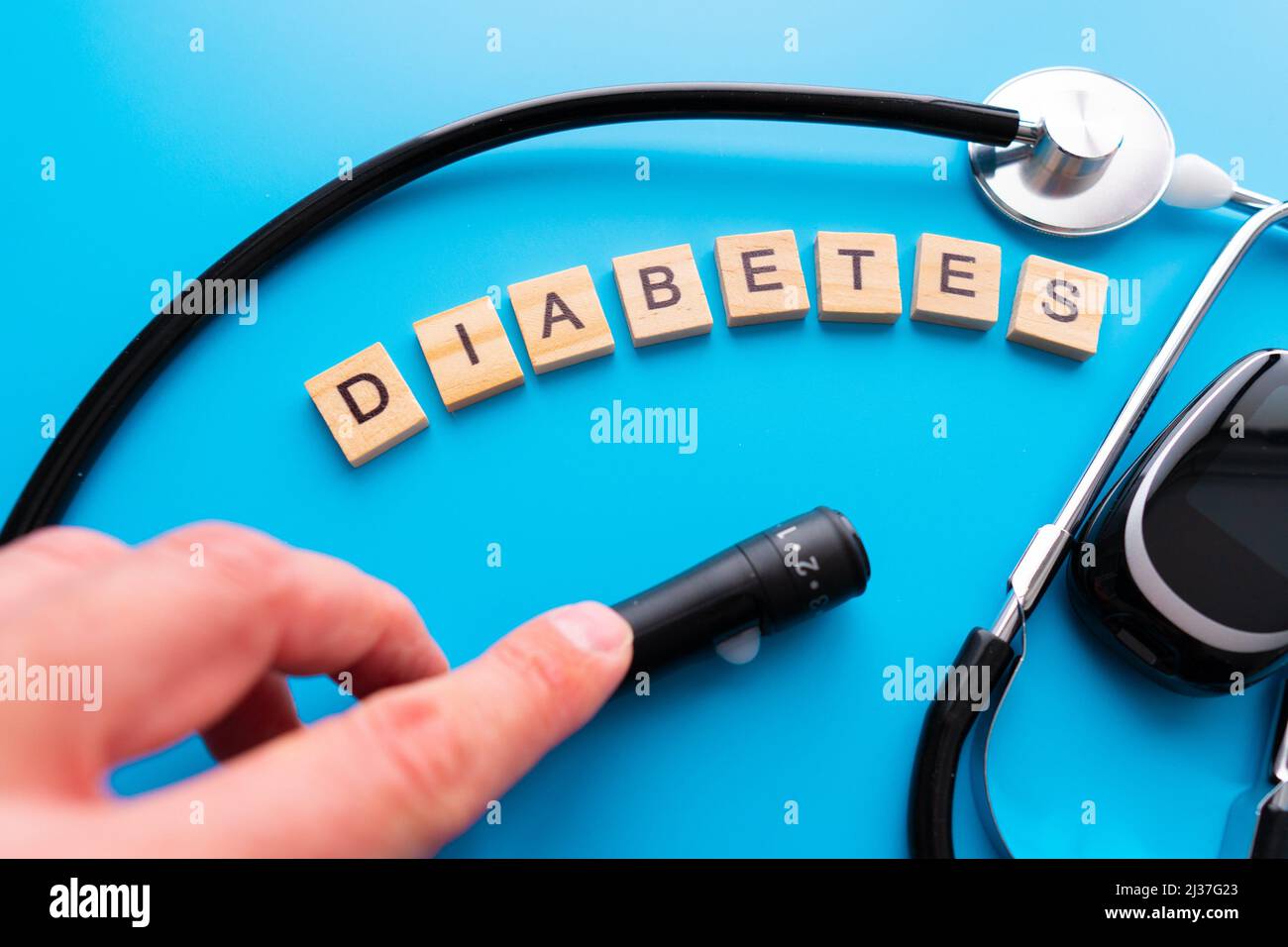 Diabetes wooden text. Flat lay composition with glucose meter and stethoscope on light blue background. Space for text. Stock Photo