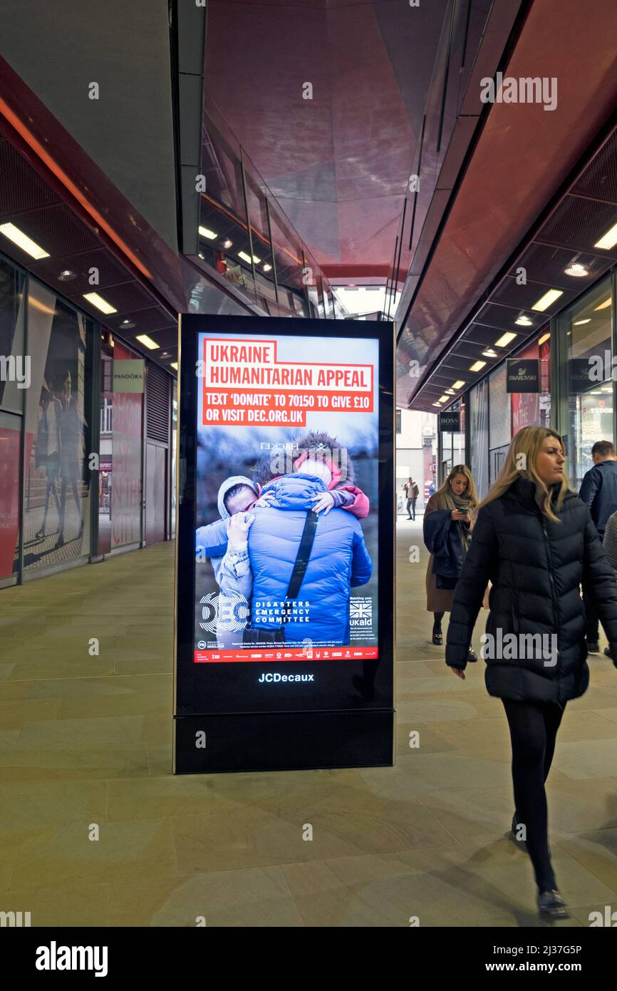 DEC Ukraine Humanitarian Appeal fundraising charity poster electronic advert and shoppers at One New Change in City of London England UK March 2022 Stock Photo