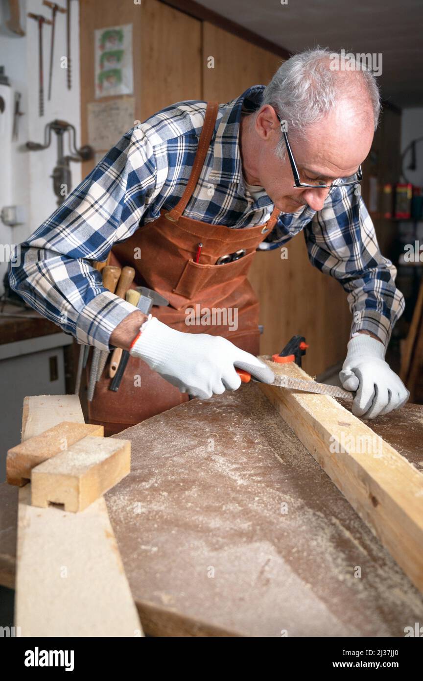 Carpenter filing a plank of wood in his Workshop. High quality photography. Stock Photo