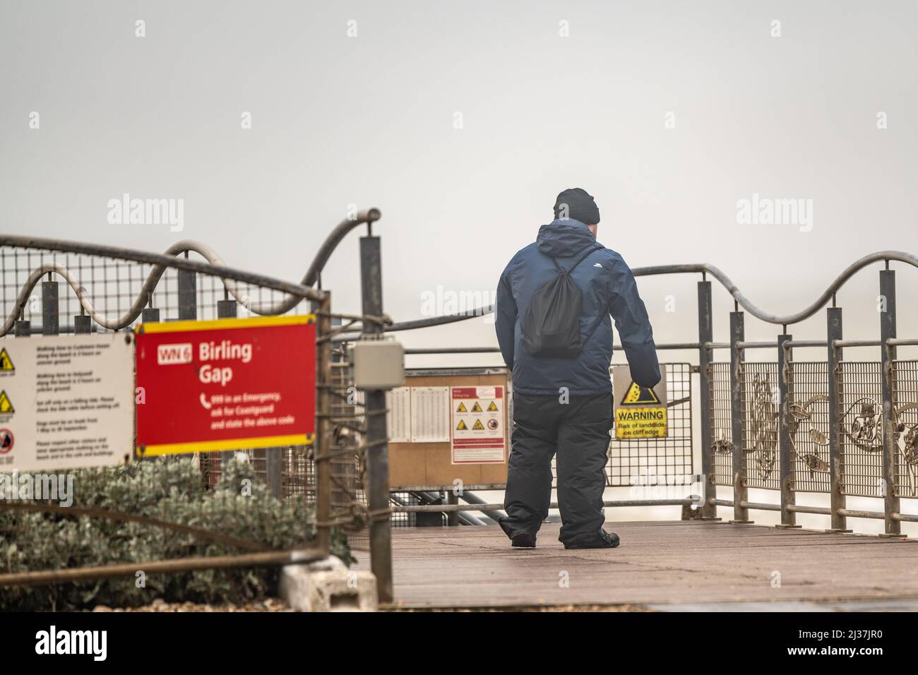 East Sussex, UK. 6th april 2022, Strong winds and heavy rain dampen the Easter school holidays as a tourist takes looks at the Seven Sisters in bad weather at  Birling Gap ,East Sussex, UK. Stock Photo