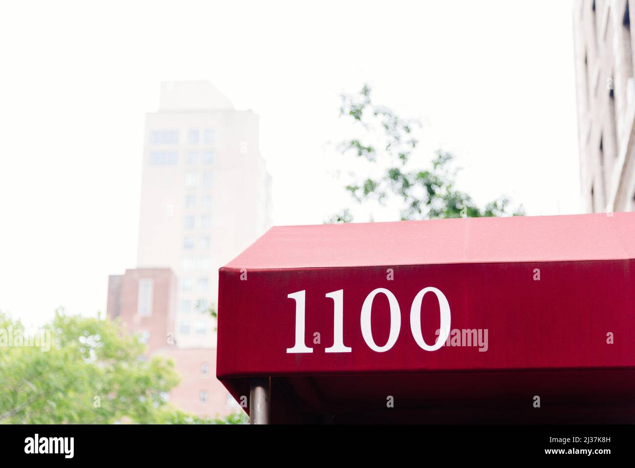 Red canopy with the number 1100 in the entrance to a luxury residential building in Manhattan, New York. Stock Photo