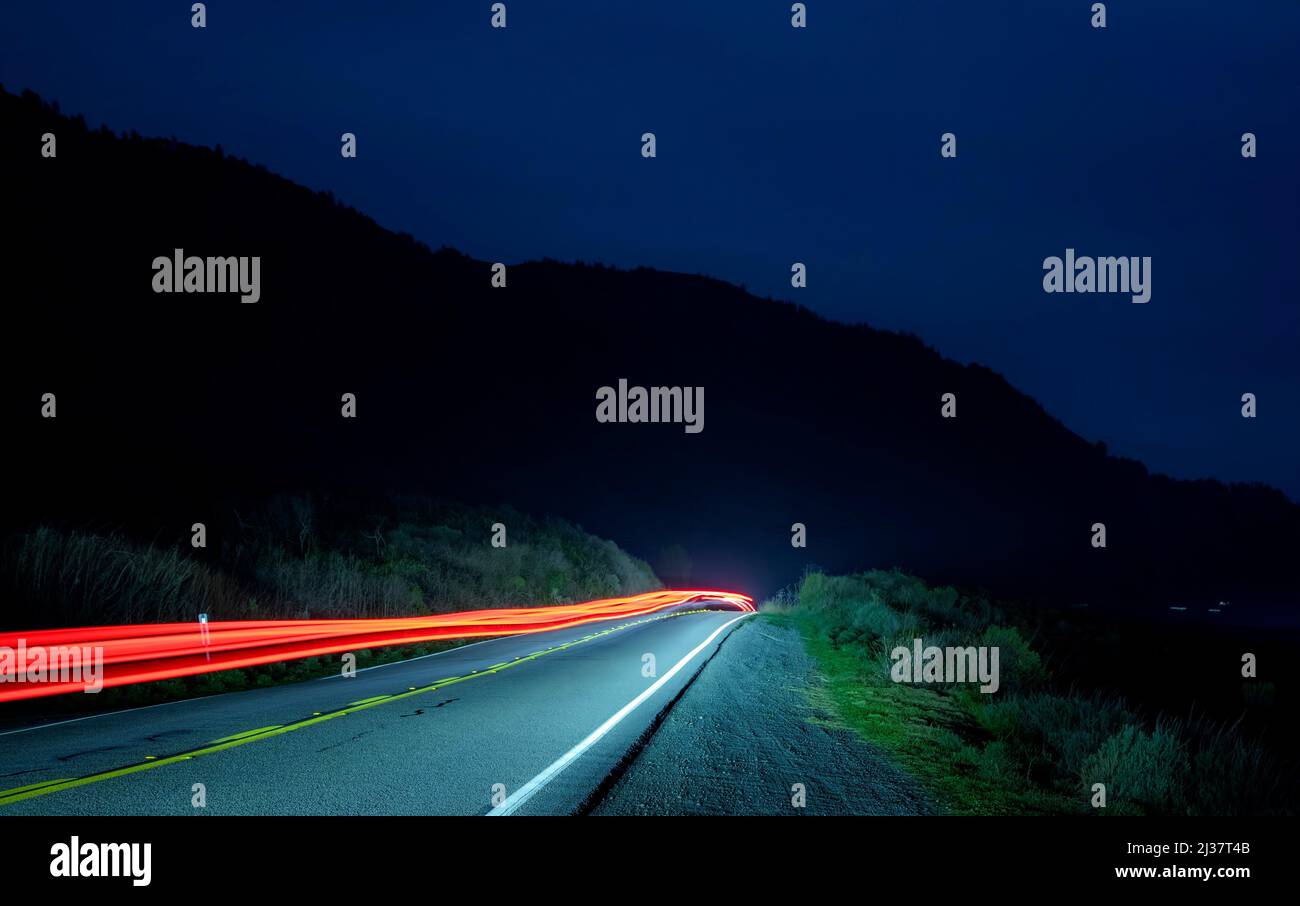 A slow exposure produces a continuos red line from a vehicle on Californiaâ.s Pacfic Coast Highway near Big Sur. Stock Photo