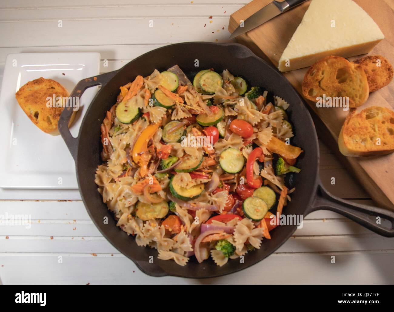 Pasta Salad With Parmesan Cheese and Garkic Bread in Cast Iron Skillet. Stock Photo