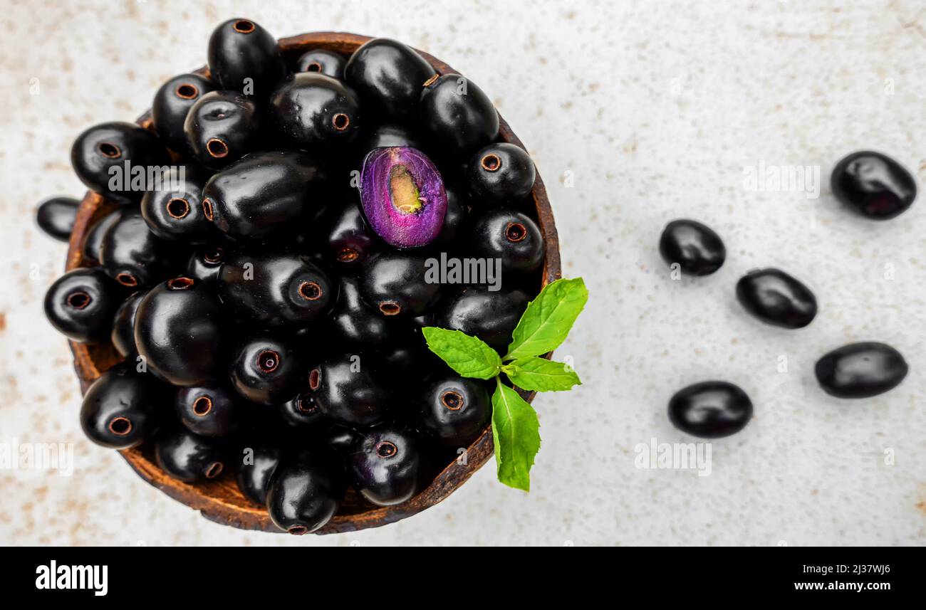 Black ripe Syzygium cumini fruits. Dark black java plum in a wood bowl