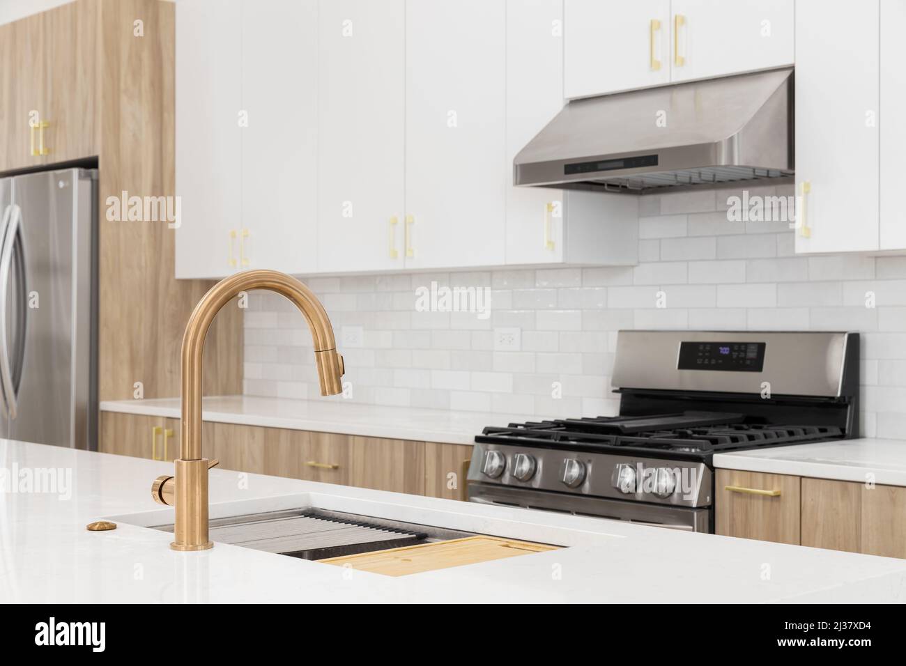 A gold faucet kitchen detail with blurred white and wood