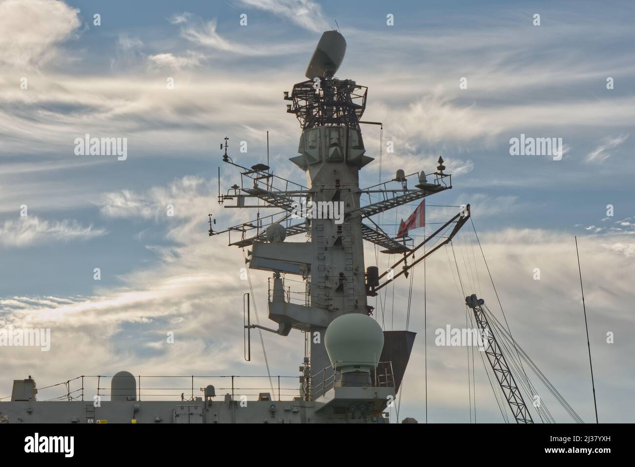 Mast with aerials and radar on British Royal Navy warship in dockyard ungoing repairs. Stock Photo