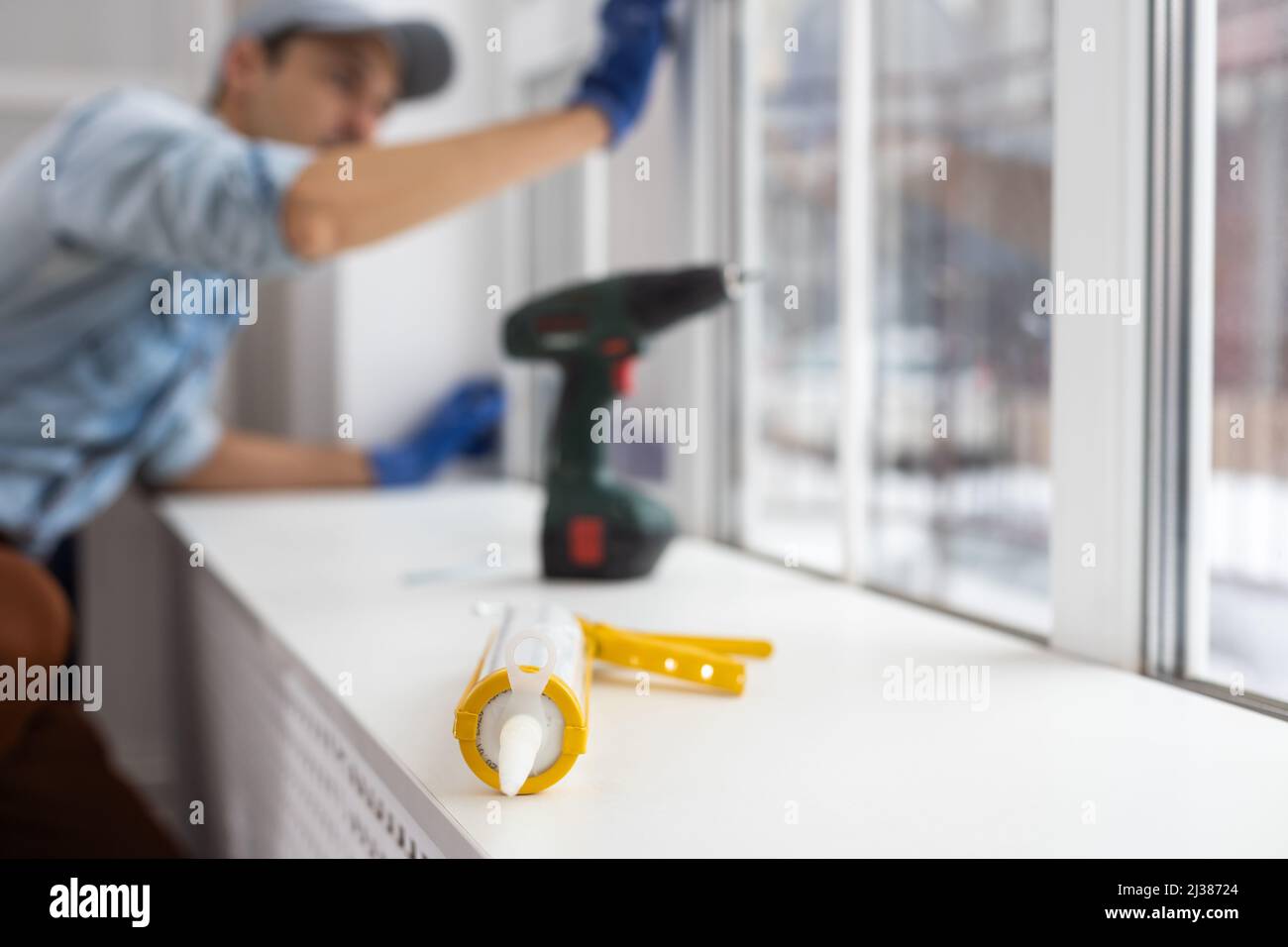 Silicone glue gun, Construction worker installing window in house
