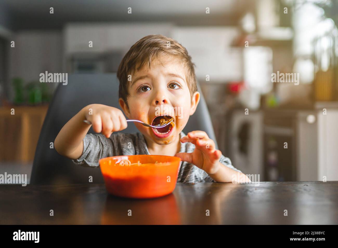 Kid eating spaghetti in the kitchen havinf fun Stock Photo Alamy