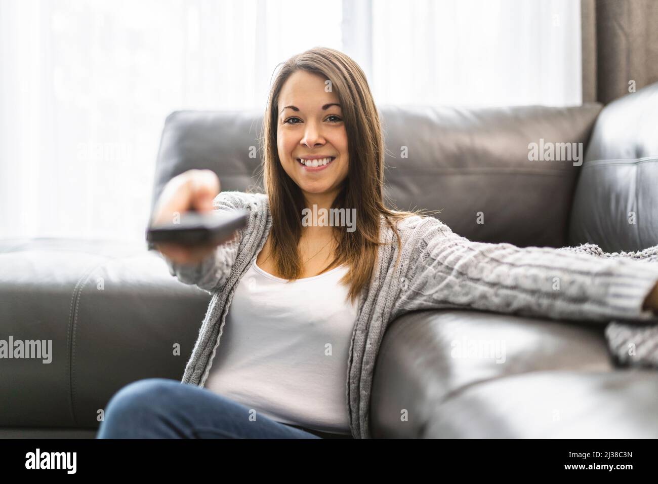 Young woman watching TV lying on the floor at home Stock Photo