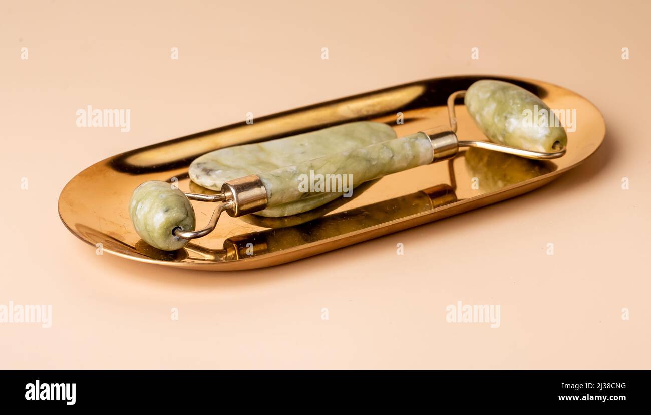 Gua Sha massage jade tools. Scraper and roller on golden stand. Lifting,  toning and anti-age treatment. Beauty and relaxation concept. High quality  photo Stock Photo - Alamy