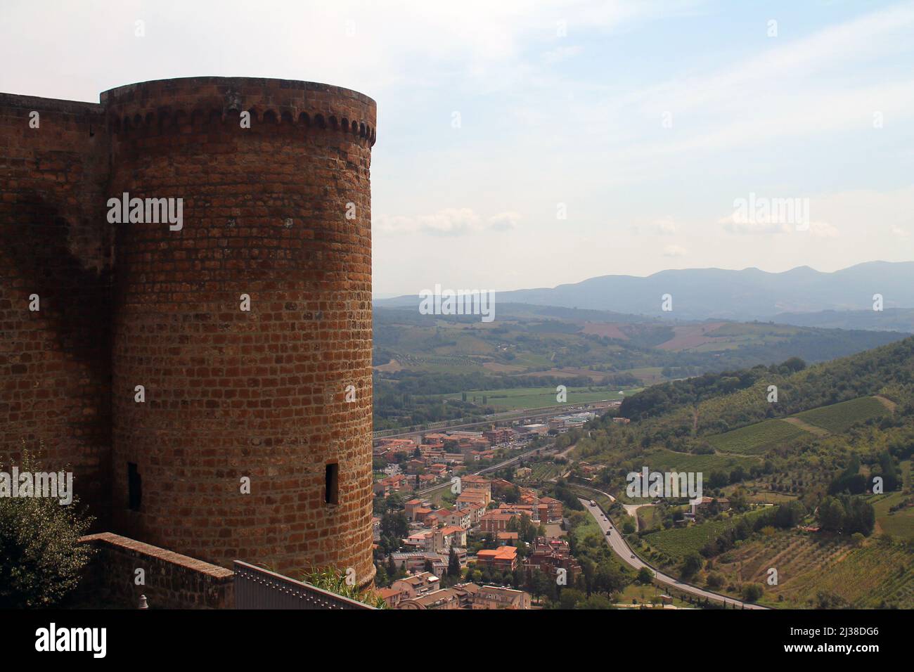Stone tower and green hills with rooftops near Orvieto in the center of Italy Stock Photo