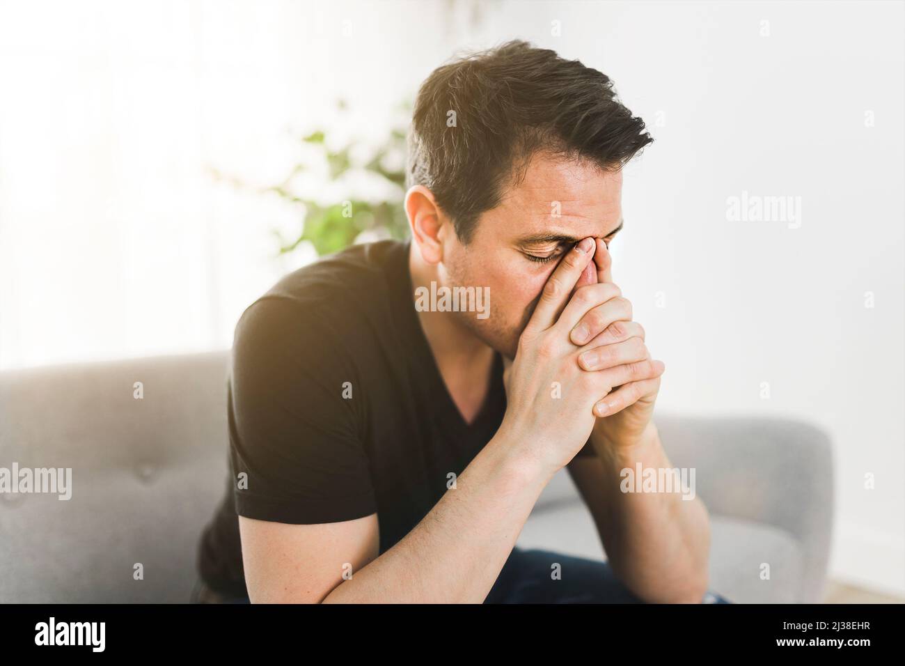 Depressed man thinking at home on couch Stock Photo