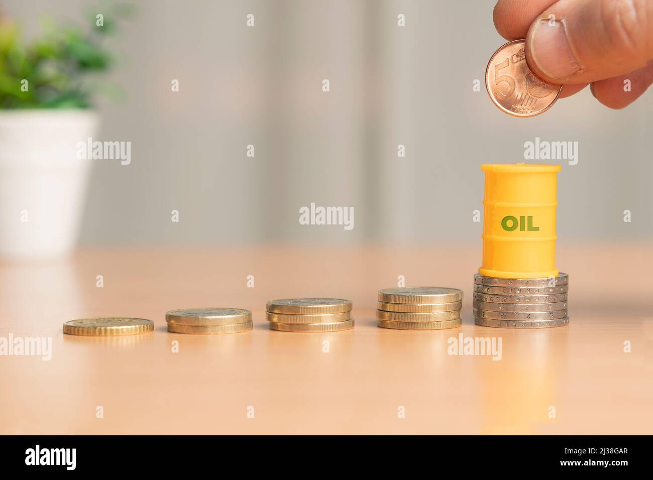 Oil price increase concept: oil barrel over a stack of coins, shallow depth of field Stock Photo