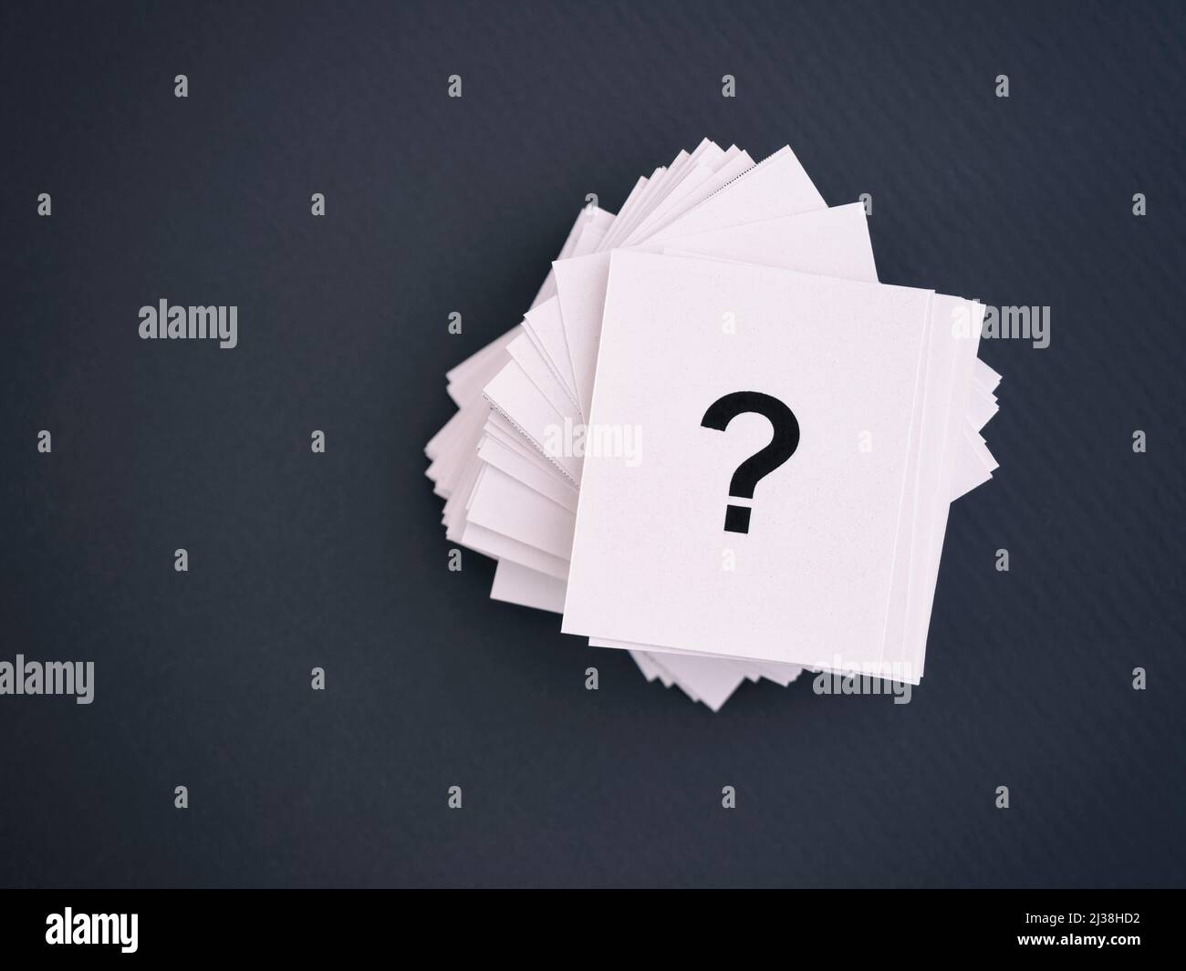 Stack of paper notes with question marks on a gray background Stock Photo