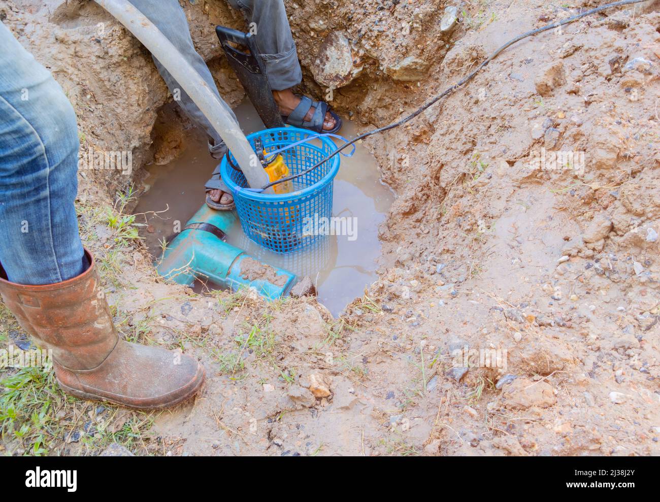 worker male repair plumbing broken plastic pipe in the hole with water flow Stock Photo