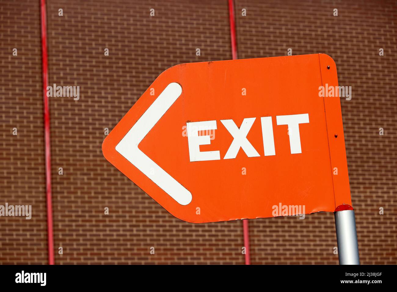Orange and white Exit sign against brick wall background Stock Photo