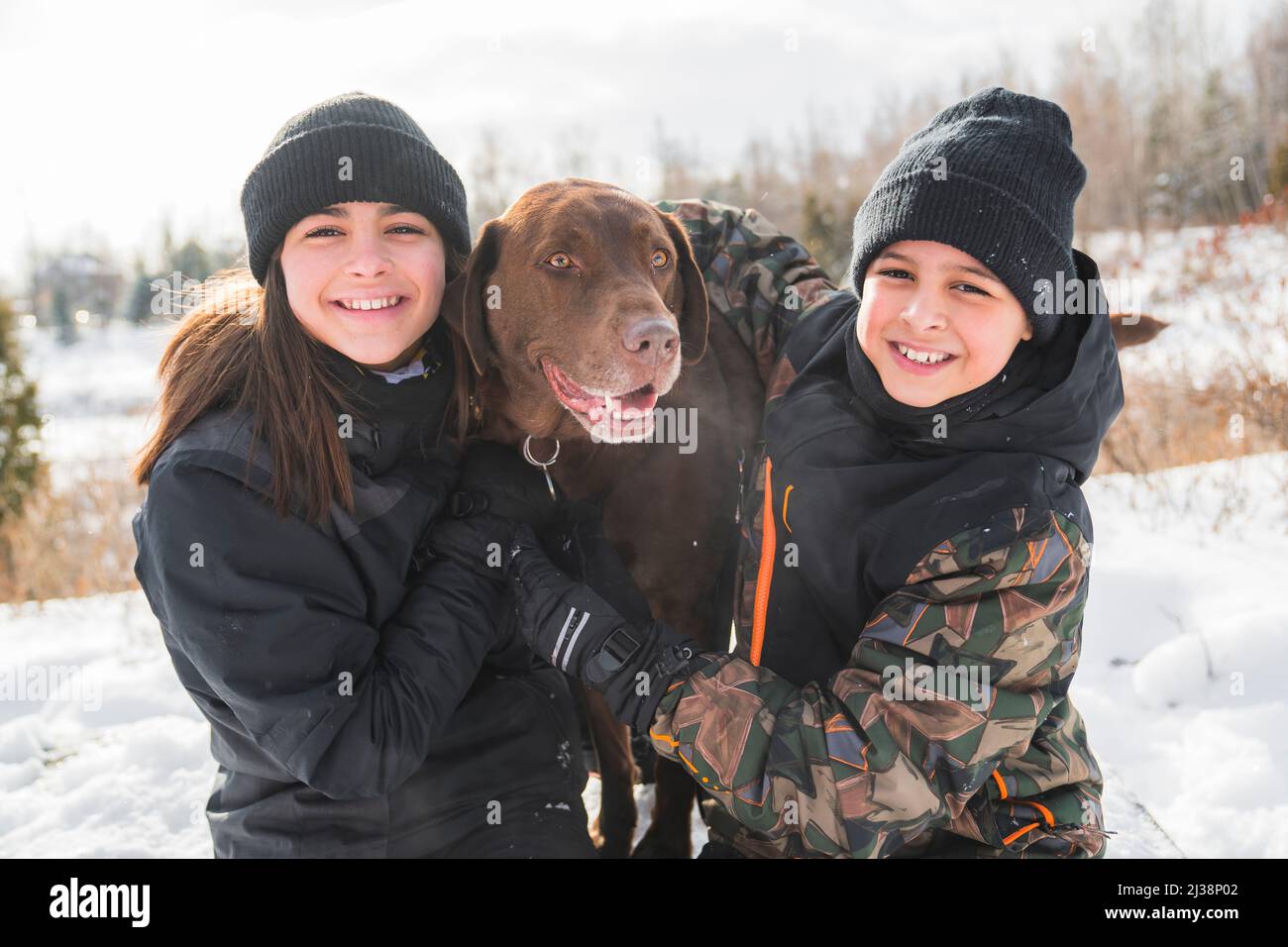 Portrait of brother and sister with labrador dog in winter season Stock Photo