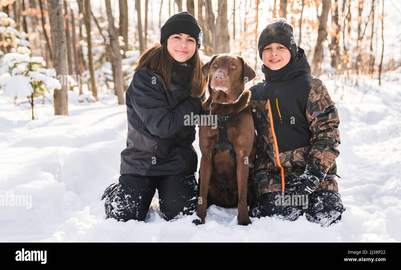 Portrait of brother and sister with labrador dog in winter season Stock Photo