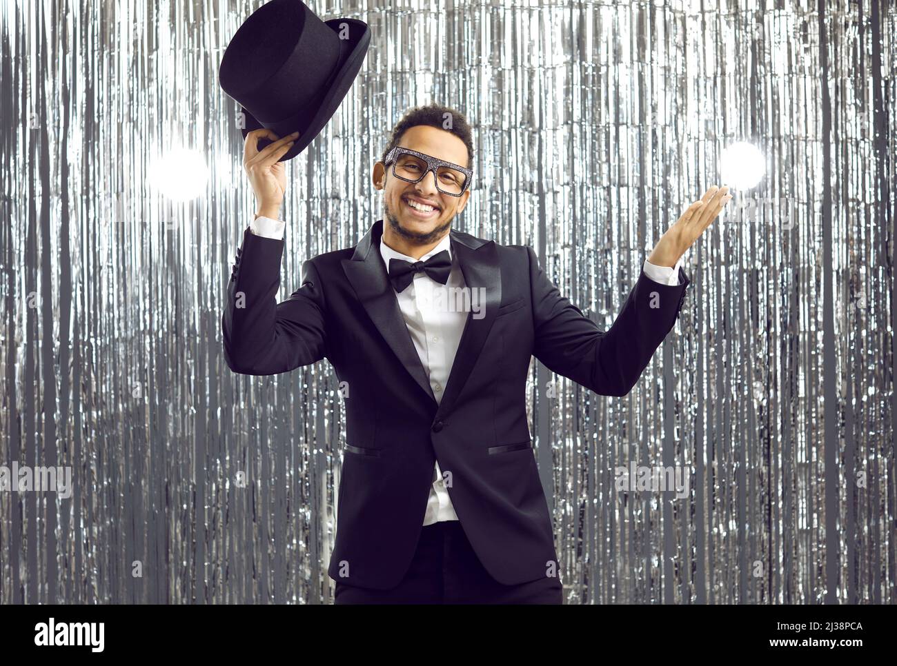 Happy smiling man in a top hat and a tuxedo with a bow tie having fun at a party Stock Photo