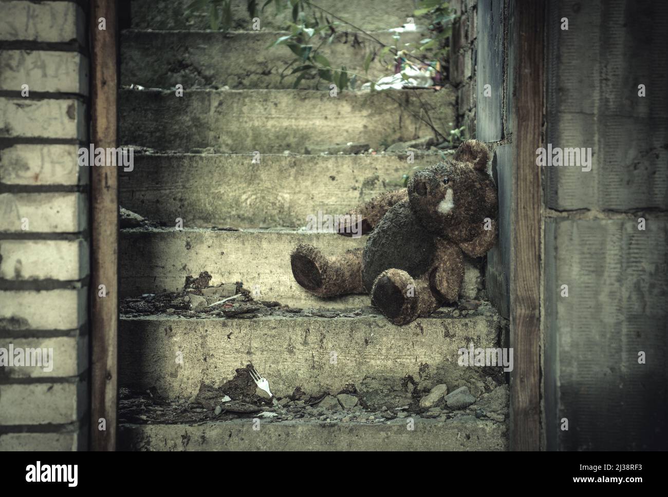 War Crimes Against Humanity Concept with Damaged Half Burned Teddy Bear Inside Residential House Ruins. Stock Photo