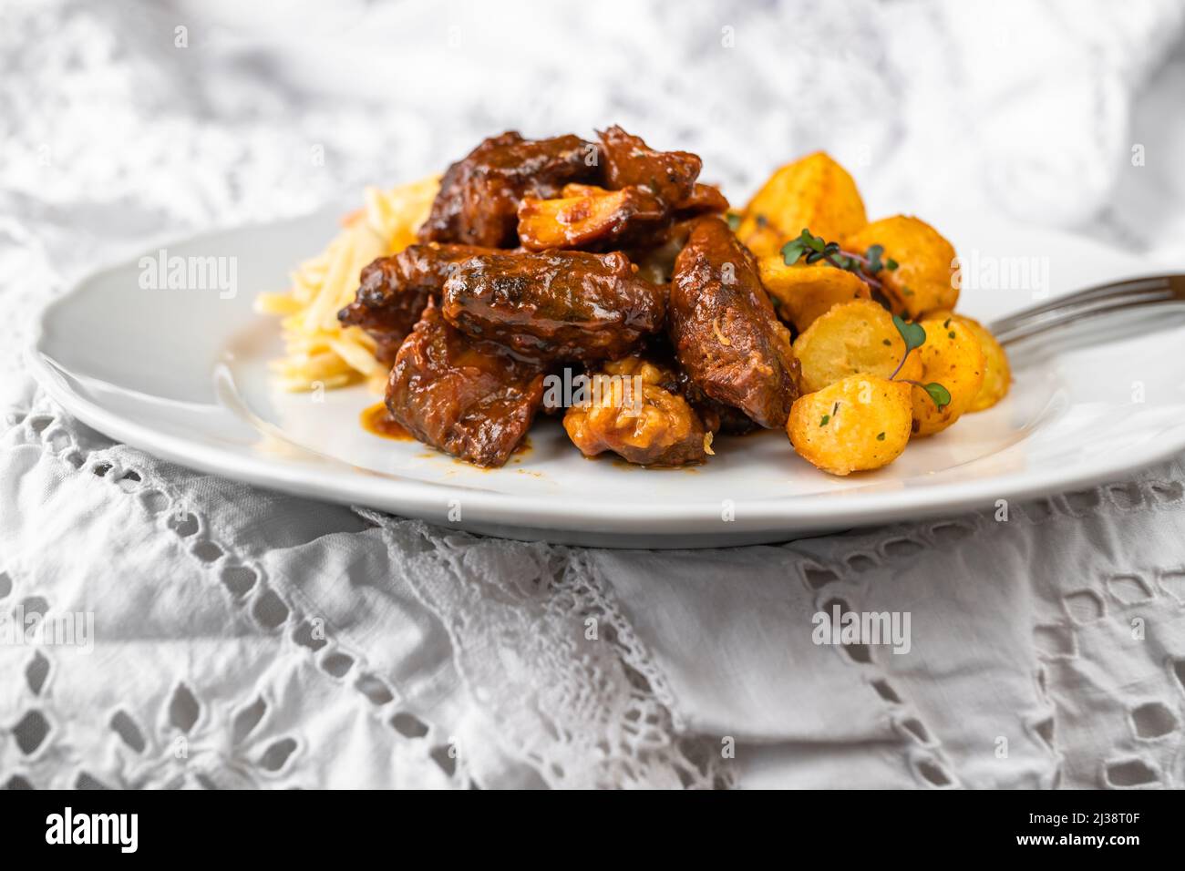 Fried sliced turkey meat in wild gypsy sauce, grilled potato and salad coleslaw on white plate, on white lacy table-cloth. closeup. Stock Photo