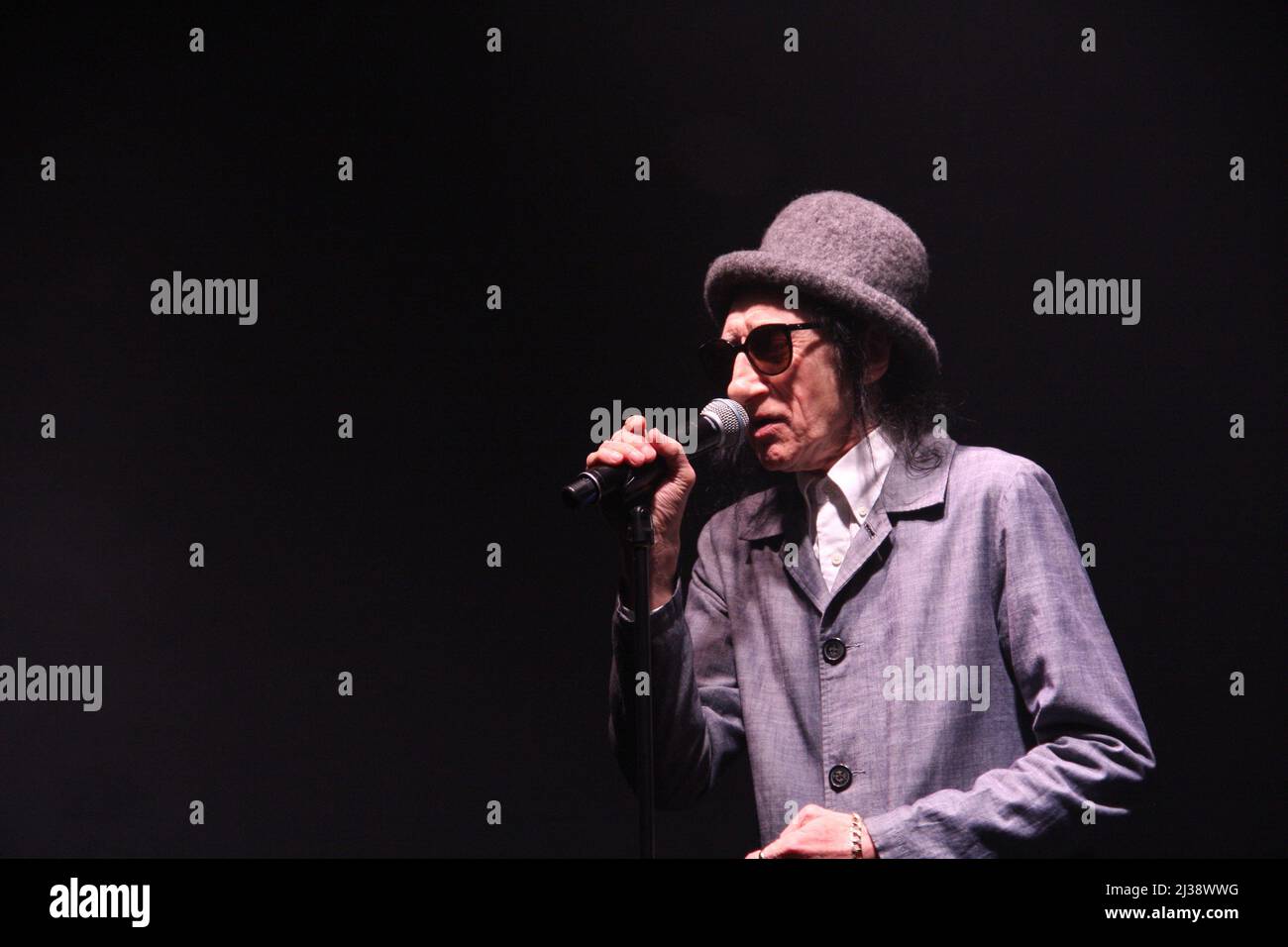 Salford-born comedian Dr John Cooper Clarke performing on stage at the Raise The Roof fundraising event at Victoria Warehouse, Manchester Stock Photo