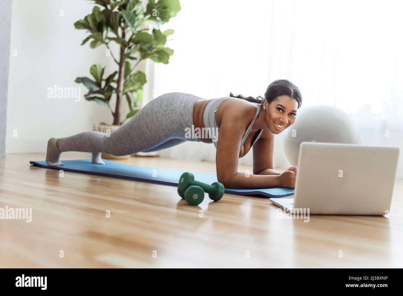 African american woman working out abdo in home livingroom gym with laptop Stock Photo