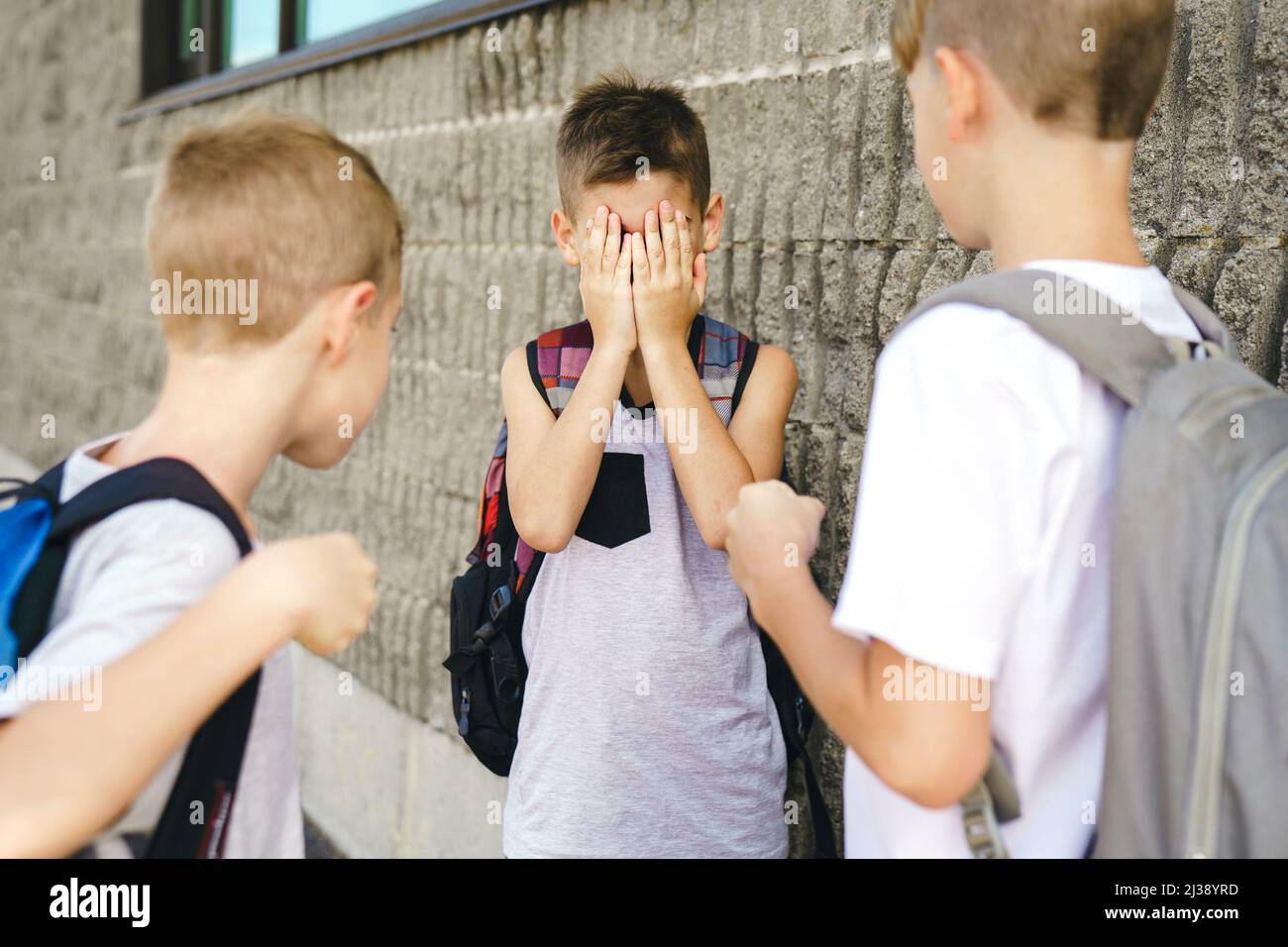 Cruel teenagers punching younger boy, physical intimidation, school bullying Stock Photo