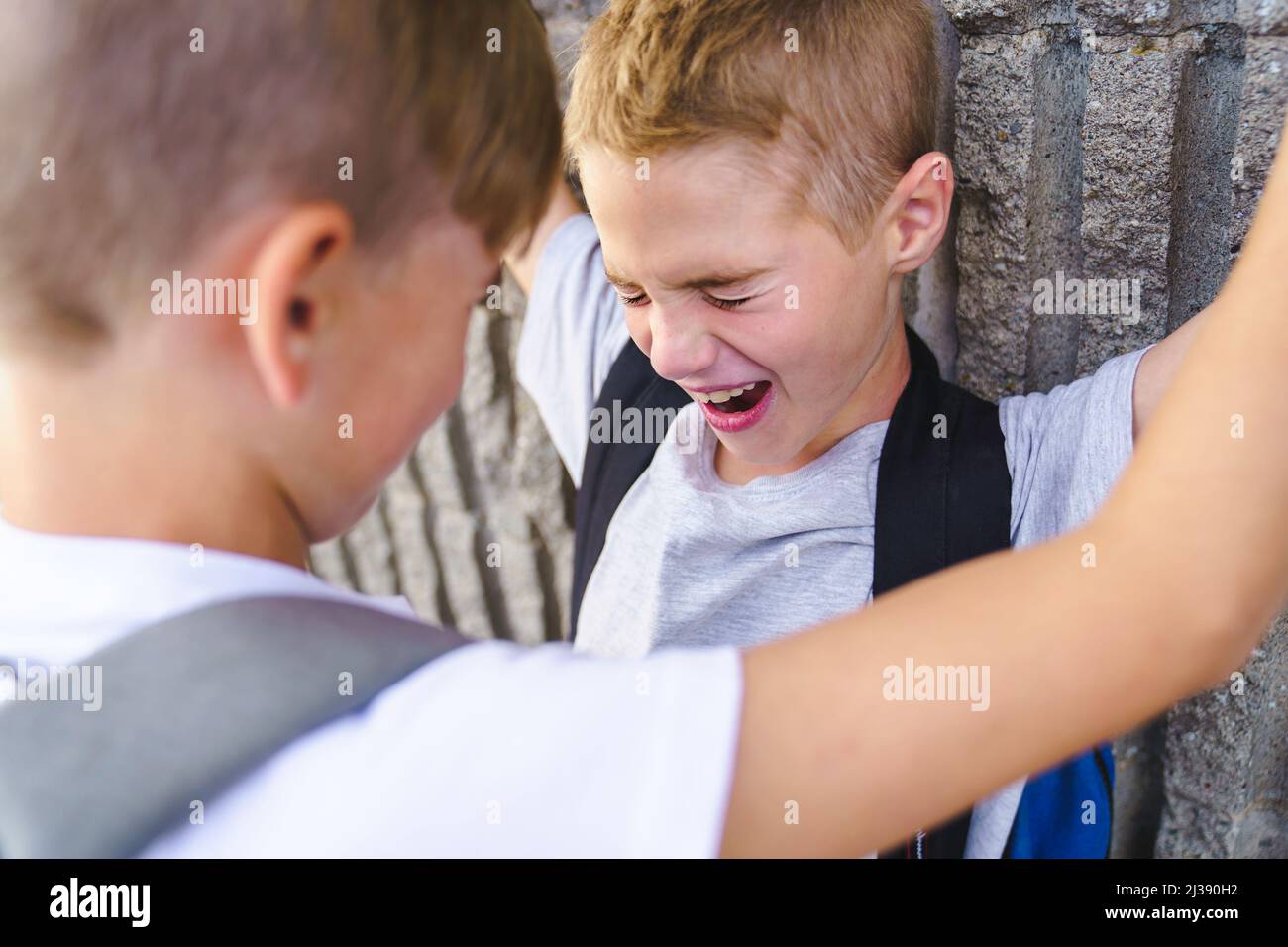 Cruel teenagers punching younger boy, physical intimidation, school bullying Stock Photo