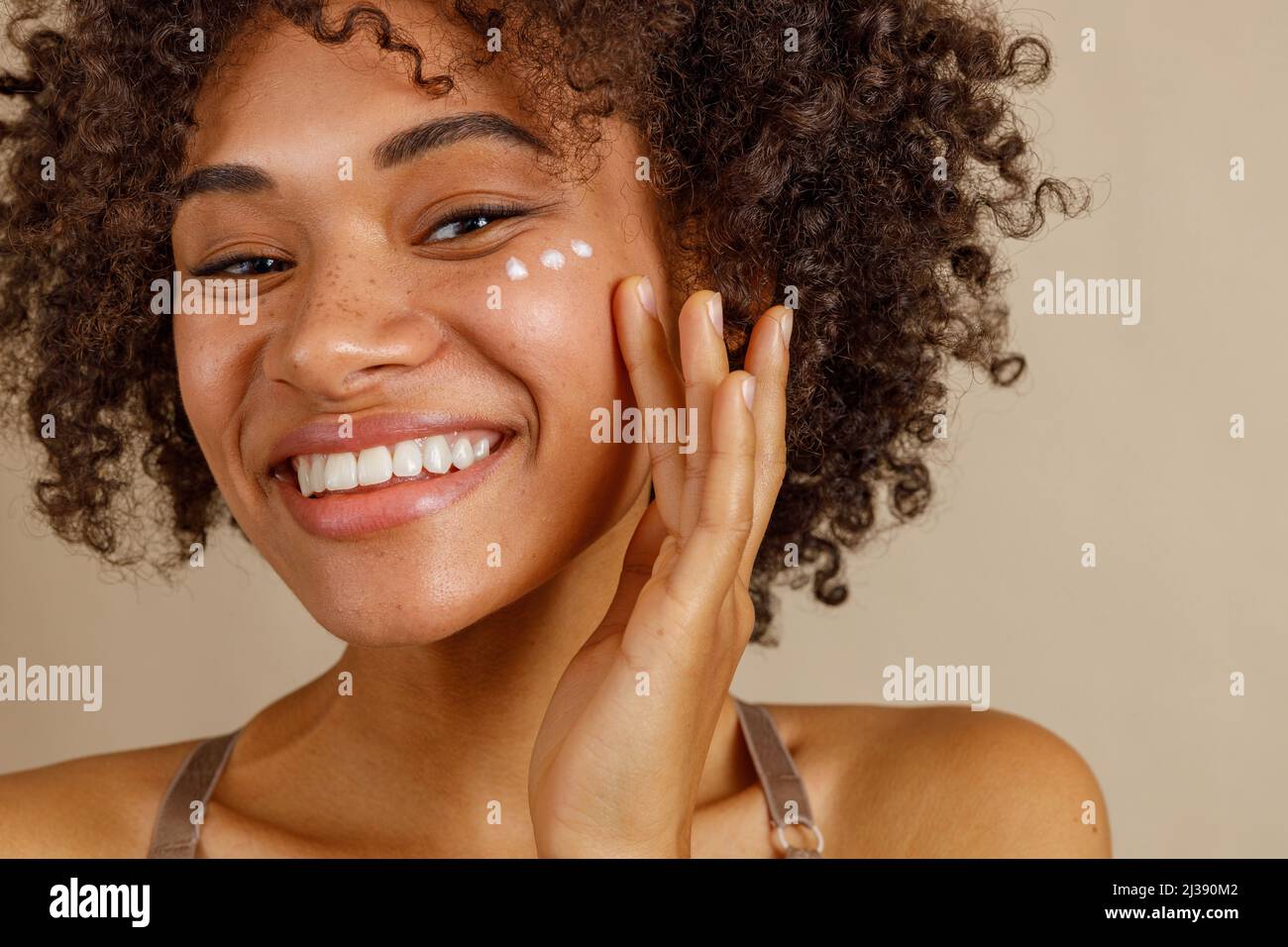 Young female model posing against beige wall Stock Photo